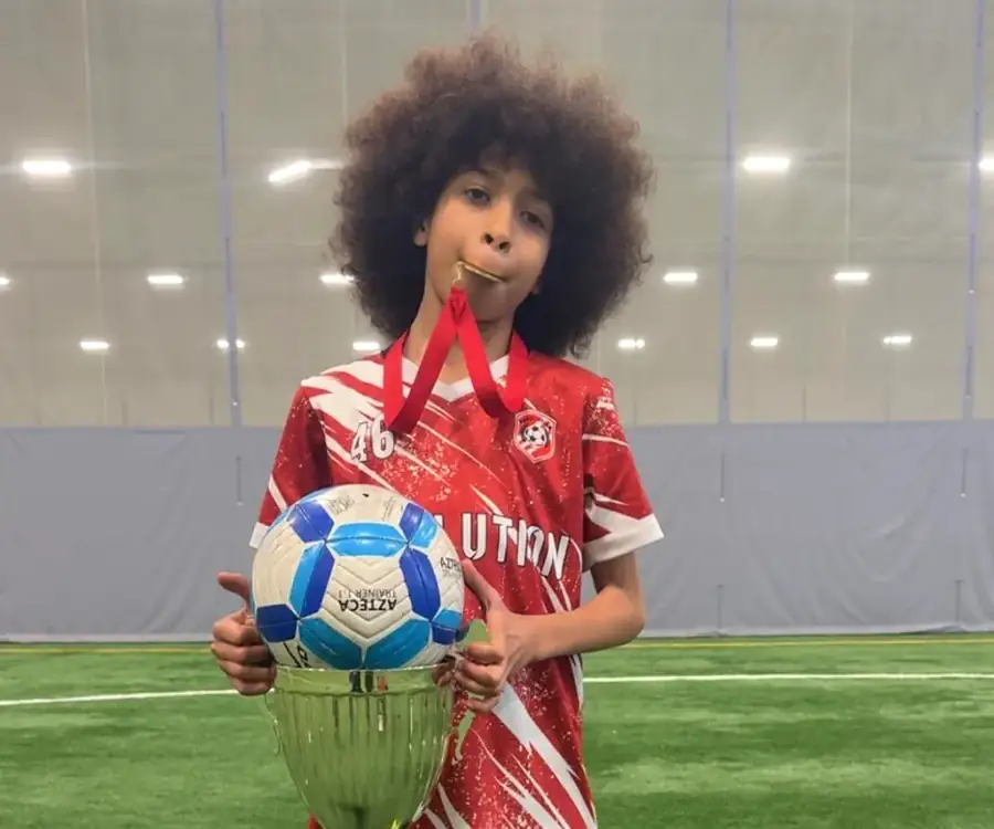 Jeune joueur Révolution posant avec son ballon et sa coupe sur le terrain intérieur